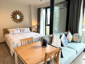 a bedroom with a bed and a couch and a table at The Deck Condominium by Lofty in Patong Beach