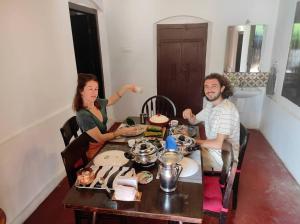 a man and a woman sitting at a table at Sukūn Heritage -A traditional 4 Bedroom Vacation Villa in Kannur