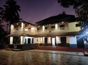 a large white building with a balcony at night at Sukūn Heritage -A traditional 4 Bedroom Vacation Villa in Kannur