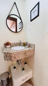 ein Bad mit einem Waschbecken und einem Wandspiegel in der Unterkunft Cantinho Paz e Amor in Nova Petrópolis
