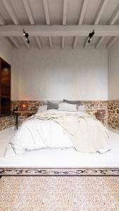 1 dormitorio con 1 cama blanca grande y pared de piedra en F Soul chill out Suite en Lindos