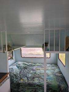a small bedroom with a bed in a tiny house at Caravan Zee by BnB de Kapitein in 't Horntje