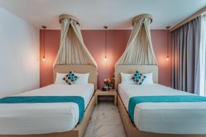 two beds in a room with red walls at Soho Playa Hotel in Playa del Carmen