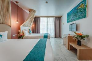 um quarto de hotel com duas camas e uma televisão em Soho Playa Hotel em Playa del Carmen