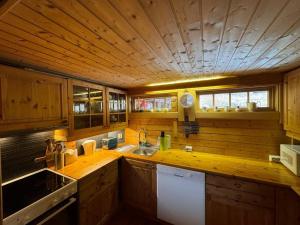 cocina con fregadero y techo de madera en Traditional Norwegian log cabin with sauna by the sea, en Tornes