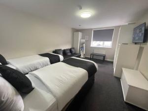 a hotel room with three beds and a flat screen tv at RYAN I AIR I BNB - 102 Mill Street - Free Parking in Liverpool