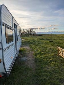 un camper parcheggiato in un campo vicino a una panchina di Caravan Zee by BnB de Kapitein a 't Horntje
