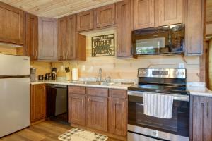 La cuisine est équipée de placards en bois et d'un four avec plaques de cuisson. dans l'établissement Lakeside Trenton Cabin on 7-Acre Property!, à Trenton