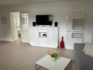 una sala de estar con TV y un jarrón de flores en Haus Meeresbrise, en Grömitz