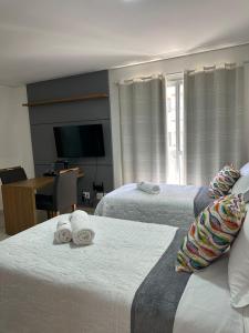 um quarto de hotel com duas camas e uma televisão em Studio 606 - Expetacular em Ribeirão Preto