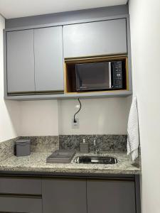 uma cozinha com um micro-ondas e um lavatório em Studio 606 - Expetacular em Ribeirão Preto