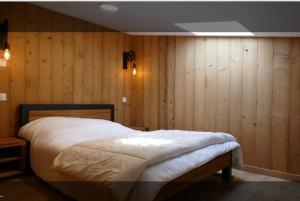ein Schlafzimmer mit einem Bett mit Holzpaneelwänden in der Unterkunft Spacieux et beau duplex au pied des pistes et centre station avec balcon in Les Deux Alpes
