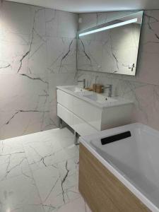 ein weißes Badezimmer mit Waschbecken und Spiegel in der Unterkunft Spacieux et beau duplex au pied des pistes et centre station avec balcon in Les Deux Alpes