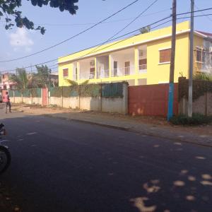 un edificio amarillo al lado de una calle en Moradia Turistica MJ ROOMS CITY, en São Tomé