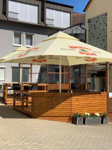 a restaurant with an umbrella on a wooden deck at Gästehaus Krone in Holzkirchen