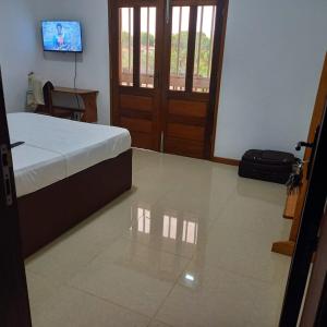 a bedroom with a bed and a television and a door at Moradia Turistica MJ ROOMS CITY in São Tomé