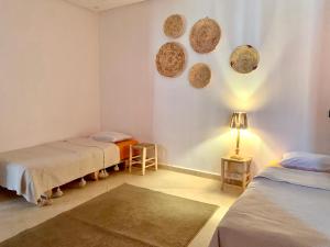 a room with two beds and a lamp on the wall at Ocean Surf House in Tamraght Ouzdar