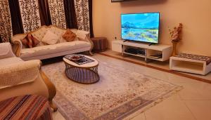 a living room with a couch and a flat screen tv at Cityscape Retreat Apartment in Sharjah