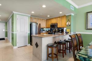 a kitchen with green walls and a bar with stools at Beachfront Bliss Luxe 3BR Condo at Marisol Complex in Panama City Beach