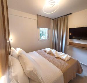 - une chambre avec un lit doté de draps blancs et une fenêtre dans l'établissement Athasi Resindences, à Thasos