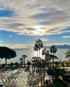 Blick auf einen Parkplatz mit Palmen und das Meer in der Unterkunft Palais Miramar in Cannes