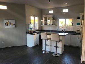 a large kitchen with two bar stools and a counter at 3A Beach Gear Equipped 2 BR Cerritos Beach Condo in San Carlos