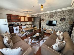 a living room with two brown couches and a kitchen at Fener Konaklama in Antalya