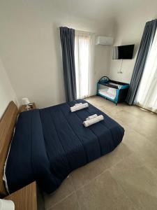 1 dormitorio con 1 cama azul y 2 toallas en Casa Ginestra di Palazzo Biondi, en Giarre