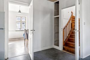 un couloir avec un escalier dans une maison aux murs blancs dans l'établissement Town House in Fuglebjerg, à Fuglebjerg
