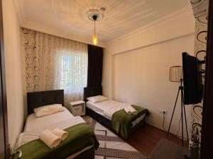 two beds in a room with a tv and a window at Fener Konaklama in Antalya