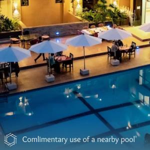 una piscina con mesas y sombrillas junto a ella en The Nest en Kigali