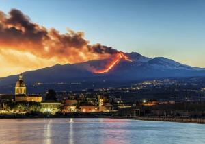una montaña con un fuego en la distancia con una ciudad en Casa Ginestra di Palazzo Biondi, en Giarre