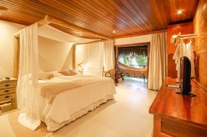 um quarto com uma cama e uma televisão num quarto em Hotel Ponta do Madeiro em Pipa