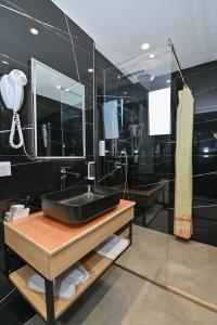 a black bathroom with a sink and a mirror at MondurO Hotel in Durrës