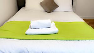 een bed met een groene deken en handdoeken erop bij KGA7- Kazi Court in Wakefield