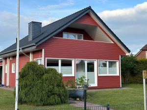 ein rotes Haus mit schwarzem Dach in der Unterkunft Ferienhaus Wiesenstrasse in Neuhaus an der Oste