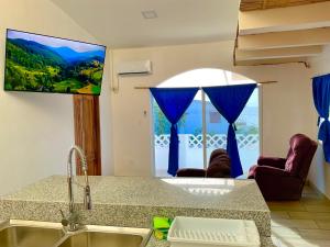 a kitchen with a large window with blue curtains at Casa de Hamacas in Ballenita