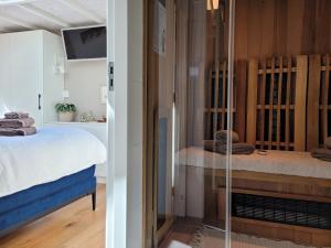 een slaapkamer met een bed en een glazen deur bij Tiny Villa de Haas met Infraroodsauna in Egmond aan Zee