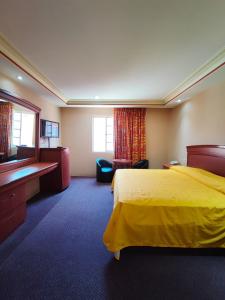 une chambre d'hôtel avec un lit jaune et une télévision dans l'établissement Auto Hotel Estrella del Sur, à Oaxaca
