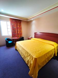 Cette chambre d'hôtel dispose d'un lit jaune et d'une fenêtre. dans l'établissement Auto Hotel Estrella del Sur, à Oaxaca