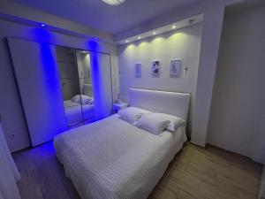a bedroom with a white bed with blue lighting at Holiday house Karla in Vela Luka