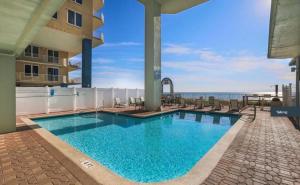a swimming pool with chairs and the ocean in the background at Beachfront Bliss Luxe 3BR Condo at Marisol Complex in Panama City Beach