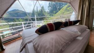 Bett in einem Zimmer mit einem großen Fenster in der Unterkunft Syameen's Glamping Dome in Kampong Kundassan