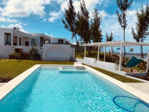 a swimming pool in front of a house at Villa Luasah in Vila Praia Do Bilene