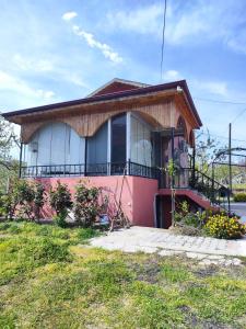 Casa pequeña de color rosa con balcón en una calle en HAS Bağ Evi 