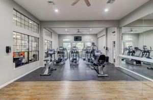 a gym with treadmills and machines in a room at Cozy Modern Apartment with patio and pool. in Houston