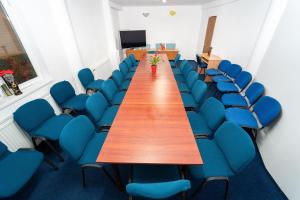einen Konferenzraum mit einem langen Tisch und blauen Stühlen in der Unterkunft Garden Resort by Cota 1200 in Predeal