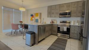 eine Küche mit Küchengeräten aus Edelstahl und einem Tisch in der Unterkunft Modern 3BR Home close to NiagaraFalls with Parking in Thorold