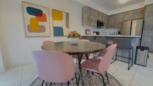 ein Esszimmer mit einem Tisch und rosa Stühlen in der Unterkunft Modern 3BR Home close to NiagaraFalls with Parking in Thorold