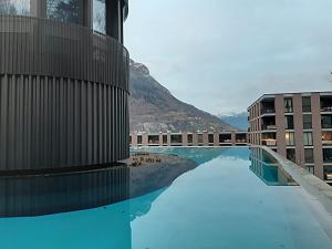 a pool with blue water next to a building at Design Loft in ehemaliger Spinnerei in Mels